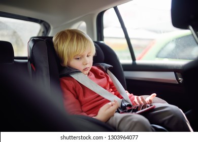 Portrait Of A Bored Little Boy Sitting In A Car Seat. Safety Of Transportation Of Children.