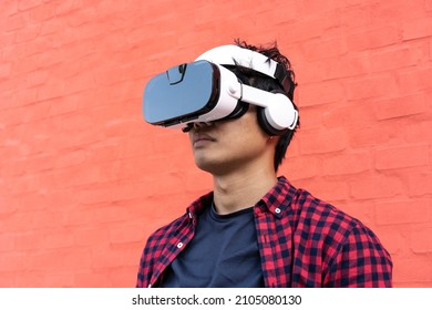 Portrait Of Bored Young Asian Man Using 3d Viewer With Headphones Outdoor - Technology And Video Game Addicted Or Futuristic Concept