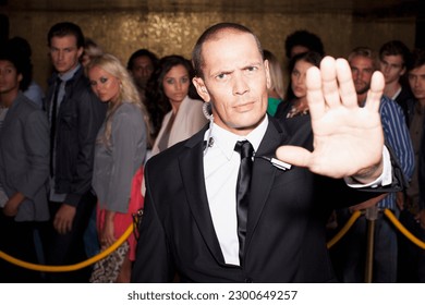 Portrait of bouncer with arm outstretched outside nightclub