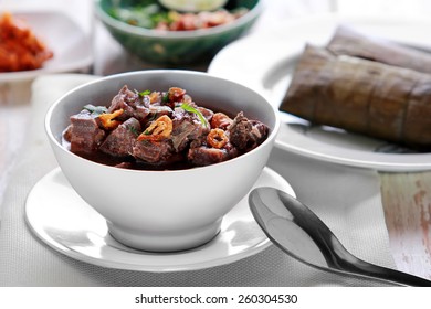 Portrait Of A Bowl Of Coto Makassar Served With Burasa