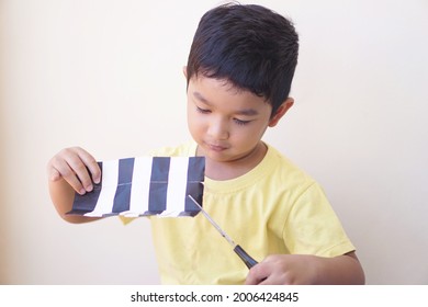 Portrait Of Boy 4-year-old. Asian Kid Holding Scissors Cutting A Paper Make Art Craft Activities Online Learning At Home. Creative Art Concept.                              