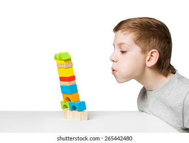 Portrait Of A Boy Blowing On Falling House Made Of Wooden Blocks