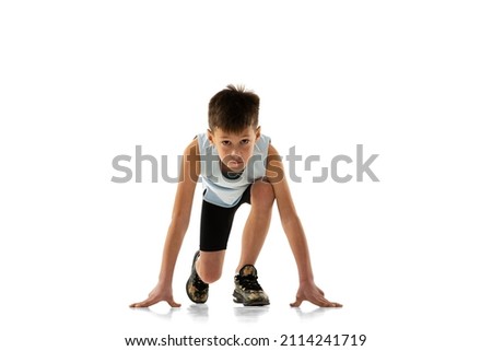 Portrait of boy, child, athlete standing on position to run isolated over white background. Ready, steady, go. Concept of action, sport, healthy life, competition, motion, physical activity and ad