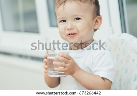 Portrait of a boy drinking a glass of water,happy in the kitchen