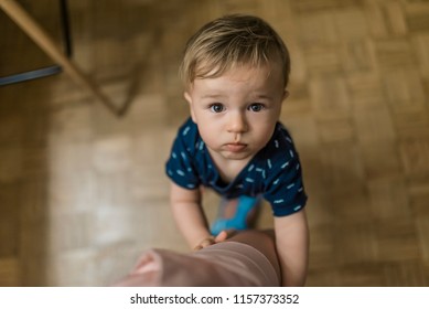 Portrait Of A Boy, Embracing Mother's Leg And Asking To Talk. Baby With Brown Eyes Holds Onto Mom Leg While Sweetly, Longingly Looking Up At His Parent. Family, Child, Childhood And Parenthood Concept