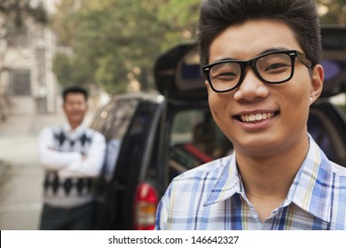 Portrait of boy in front of car on college campus
