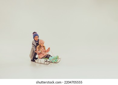 Portrait Of Boy And Girl, Children In Winter Clothes Sledding Isolated Over Grey Studio Background. Winter Holidays. Concept Of Childhood, Friendship, Fun, Lifestyle, Fashion, Retro Style