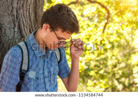 portrait of a boy in glasses nerd on a tree background