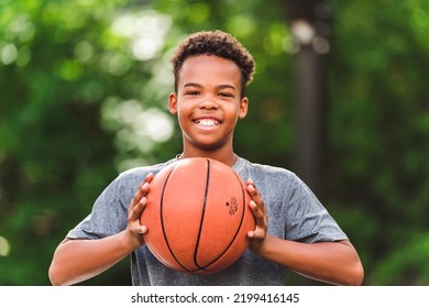 A portrait of a boy kid playing with a basketball in park - Powered by Shutterstock