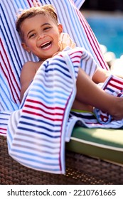 Portrait Of Boy On Summer Holiday On Lounger By Swimming Pool Eating Ice Cream