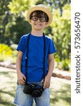 Portrait of boy posing with a camera around his neck in park