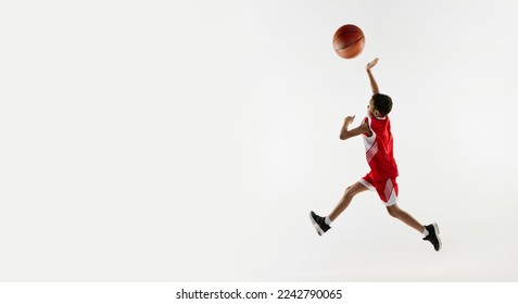 Portrait of boy in red uniform training, playing basketball over grey studio background. Banner. Concept of energy, professional sport, motion, action, hobby, competition, achievement. - Powered by Shutterstock