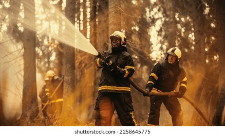 Portrait of a Brave Professional African Firefighter Using a Firehose to Fight a Raging Dangerous Forest Fire. Experienced Black Fireman Skillfully Manages the High-Pressure Water and Stays Safe. - Shutterstock ID 2258645775