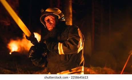 Portrait of a Brave Professional Firefighter Using a Firehose to Fight a Raging Dangerous Forest Fire. Experienced Fireman Skillfully Manages the High-Pressure Water and Stays Safe. Low Angle Shot. - Shutterstock ID 2258645613