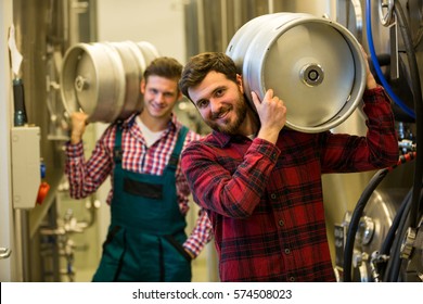 Portrait of brewers carrying keg on shoulder at brewery factory - Powered by Shutterstock