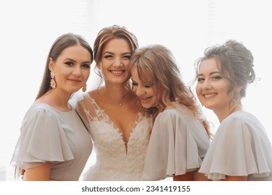 Portrait of the bride with her friends. The bride in a voluminous white dress and her beautiful friends in white evening dresses are posing. Brunettes. Open shoulders. Morning of the bride. - Powered by Shutterstock