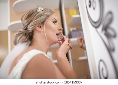 Portrait Of Bride Putting On Make Up . The Bride Putting On Lipstick In Living Room Front Of Mirror