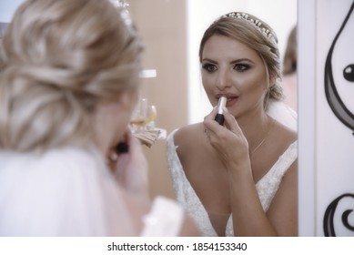 Portrait Of Bride Putting On Make Up . The Bride Putting On Lipstick In Living Room Front Of Mirror