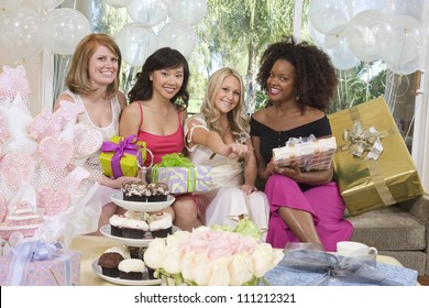 Portrait Of Bride Showing Her Engagement Ring And Friends Holding Gifts At Party