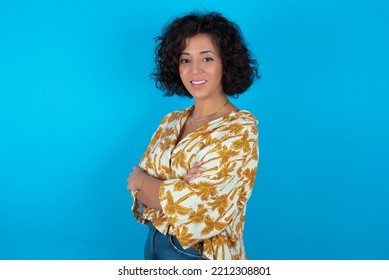 Portrait Of Brunette Arab Woman Wearing Hawaiian Shirt Over Blue Background Standing With Folded Arms And Smiling