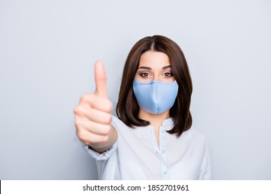 Portrait Of Brunette Girl In Blue Fabric Face Mask Gesturing Thumb Up Symbol Front To The Camera Isolated On Grey Background