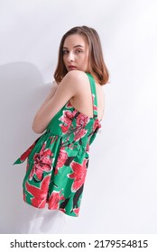 Portrait Of A Brunette Young Woman In Summer Floral Pattern Print. Shirt,with White Pants,posing In Studio

