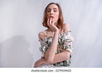 Portrait Of A Brunette Young Woman In Summer Floral Pattern Print. Shirt,with White Pants With Palm Shadow