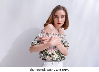 Portrait Of A Brunette Young Woman In Summer Floral Pattern Print. Shirt,with White Pants With Palm Shadow