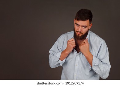 Portrait Of Brutal, Bearded, Aggressive, Big Person In Blue Shirt On Dark Background. Angry Human Bodyguard With Stern Look. Mafia Man Is Ready To Protect Against Violence And Underground. Copy Space