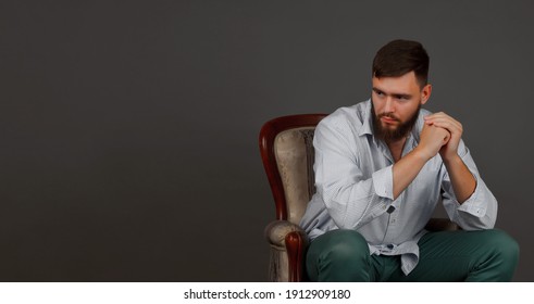 Portrait Of Brutal, Bearded, Serious, Big Person On Chair, Dark Background. Kind Thoughtful Human Bodyguard With Stern Look. Mafia Man Is Ready To Protect Against Violence And Underground. Copy Space