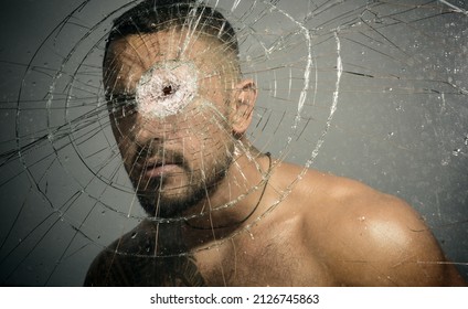Portrait of brutal man with serious face. Gangster man. Dangerous criminal, hooligan guy on cracked bullet glass.