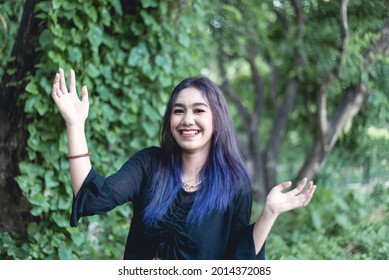 Portrait Of A Bubbly, Animated And Cheerful Asian Goth Girl With Purple Dyed Hair Posing Outdoors.