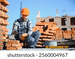 Portrait of a builder in the process of working on a construction site outdoors.