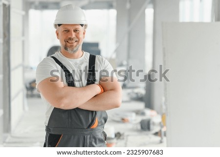 Portrait of a builder in the process of working on a construction site indoors.