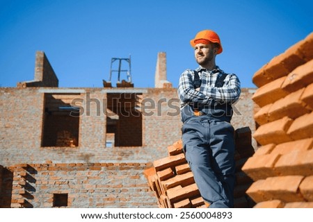 Portrait of a builder in the process of working on a construction site outdoors.