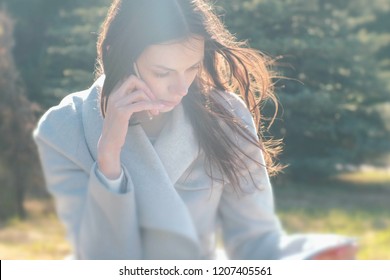 Portrait Of Buisness Woman Sitting In The Spring Park On The Grass And Talking On A Mobile Phone.