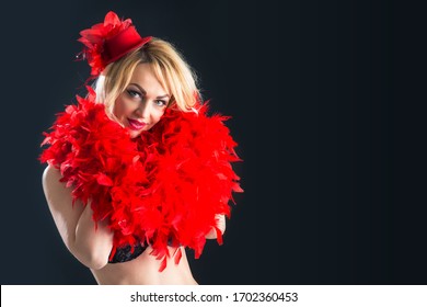 Portrait of a burlesque woman with red boa. Studio shot on black background.