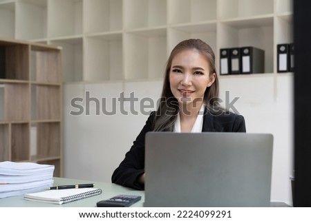 Portrait business asian woman looking on camera while using laptop computer.