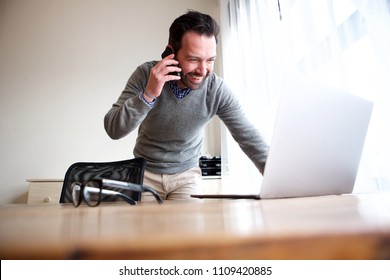 Portrait Of Business Man Talking On Mobile Phone And Looking At Computer