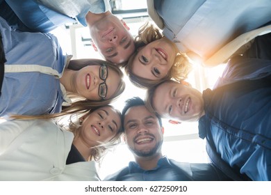 Portrait of business team in modern bright office embraced looking down to the camera