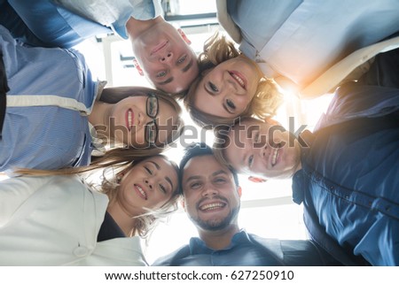 Portrait of business team in modern bright office embraced looking down to the camera