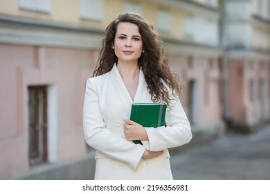 The Portrait Of A Business Woman With A Notebook In Her Hand.  Smartly Dressed Girl Outside. Successful White European Woman