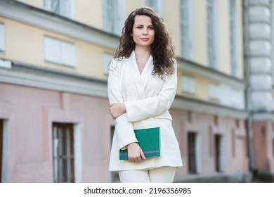 The Portrait Of A Business Woman With A Notebook In Her Hand.  Smartly Dressed Girl Outside. Successful White European Woman