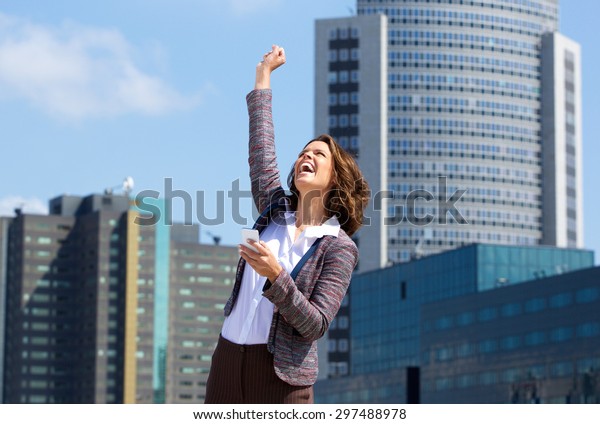 Portrait of a business woman punching the air\
with joy after reading text\
message