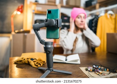 Portrait of a business woman showing customers latest arrivals in store - Young female sells products online - Millennial sponsors clothing with video review, focus on smartphone - Start up concept - Shutterstock ID 2131670275