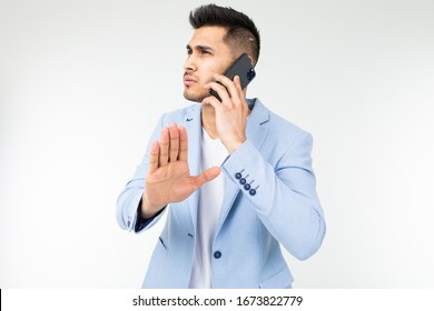 Portrait Of A Businessman In A Blue Jacket Talking Seriously With Partners On The Phone With The Expression Do Not Interrupt On A White Background