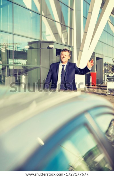 Portrait of\
businessman calling for taxi in airport\
