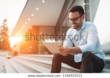 Portrait of businessman in glasses holding tablet