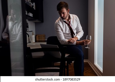 Portrait of businessman at home resting after long day at work having video call at kitchen using laptop. - Shutterstock ID 1897083529