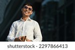 Portrait businessman in photochromic glasses standing outside building. Modern lifestyle and technology concept